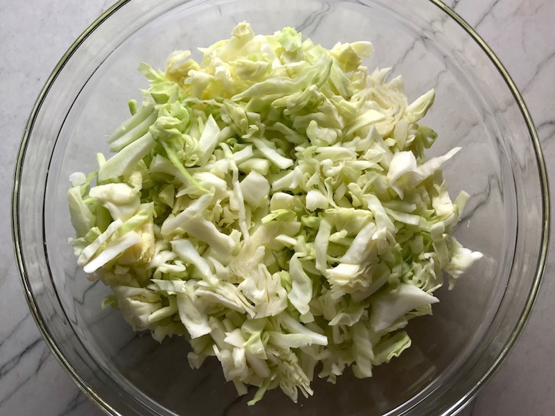 Thinly sliced cabbage thin for Asian Coleslaw. It has cabbage, carrots, scallions, and sesame seeds in a creamy dressing with mayonnaise. vinegar, soy sauce, and Sesame Oil. It really is a sidekick that can go with anything!