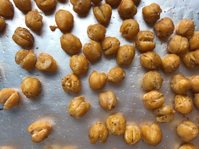 Close up of chickpeas that have been roasted on a pan. Creamy Carrot Soup with Kale, Roasted Chickpeas and Thyme is a creamy, textured, easy-to-make soup! It's great as a starter, but hearty enough to be a meal with Kale and Chickpeas. Not only does this soup taste delicious, it's also incredibly healthy with vitamins, nutrients, fiber, and protein!