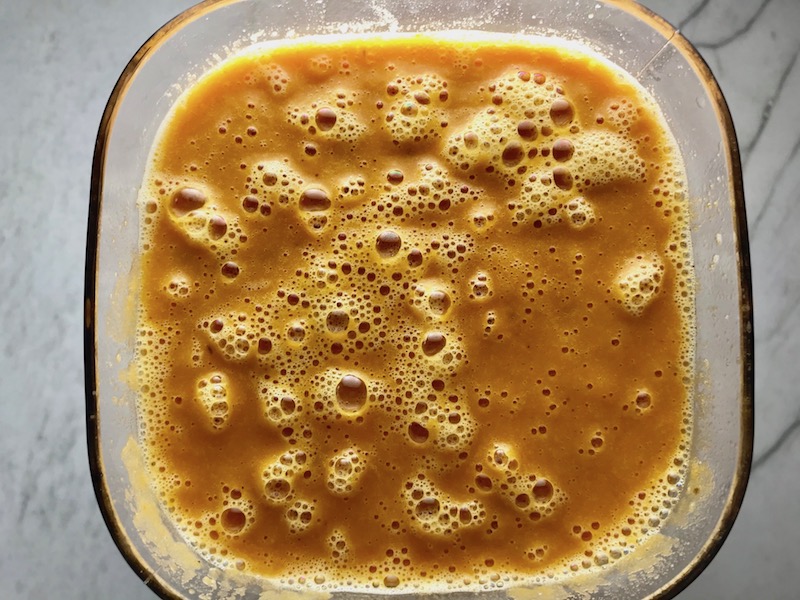 Carrot soup blended in blender from the top view. Creamy Carrot Soup with Kale, Roasted Chickpeas and Thyme is a creamy, textured, easy-to-make soup! It's great as a starter, but hearty enough to be a meal with Kale and Chickpeas. Not only does this soup taste delicious, it's also incredibly healthy with vitamins, nutrients, fiber, and protein!