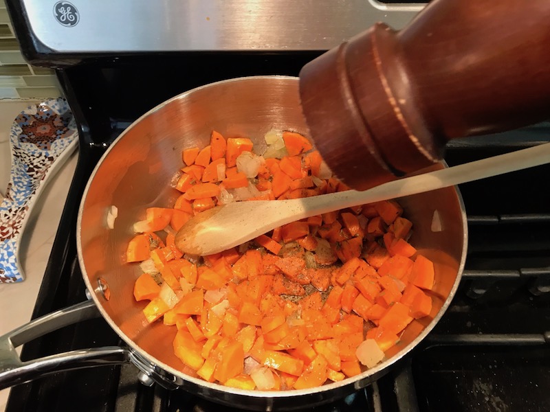 Carrots and Onion in pot with wood spoon and adding pepper. Creamy Carrot Chickpea Soup with Kale, Roasted Chickpeas and Thyme is a creamy, textured, easy-to-make soup! It's great as a starter, but hearty enough to be a meal with Kale and Chickpeas. Not only does this soup taste delicious, it's also incredibly healthy with vitamins, nutrients, fiber, and protein!