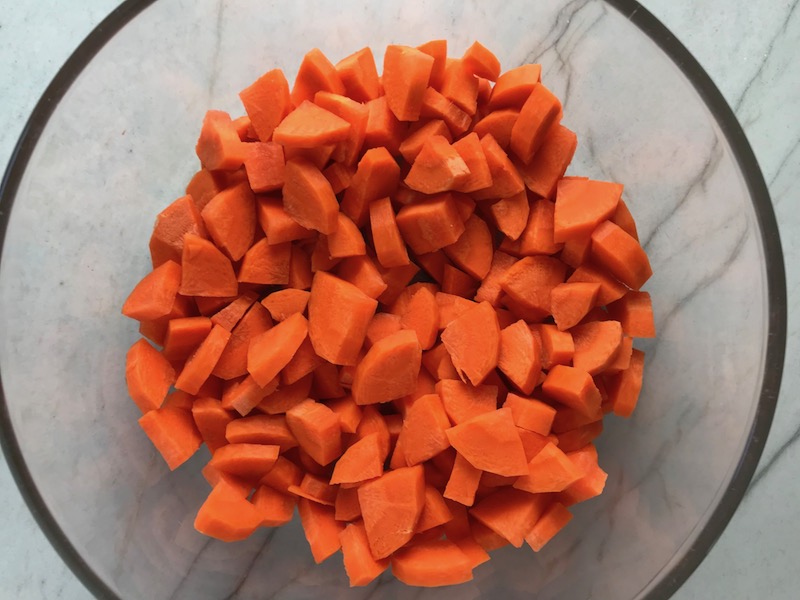 Diced Carrots in clear bowl on counter. Creamy Carrot Soup with Kale, Roasted Chickpeas and Thyme is a creamy, textured, easy-to-make soup! It's great as a starter, but hearty enough to be a meal with Kale and Chickpeas. Not only does this soup taste delicious, it's also incredibly healthy with vitamins, nutrients, fiber, and protein!