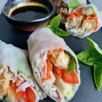 Teriyaki Chicken Summer Rolls with carrots, basil, red pepper and rice noodles inside, cut in half and stacked on slate platter with Garlic Honey Soy Dipping Sauce. Easy, fun, and delicious!