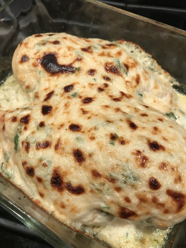 Creamy Garlic Parmesan Chicken browned on top in casserole dish.