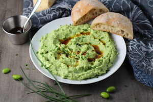Edamame Dip with Gorgonzola and Harissa Oil drizzled on top on a plate with bread. It's creamy, savory, nutty, and utterly delicious!