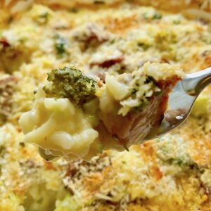Cheesy Chicken Sausage Broccoli Rice Casserole bite on fork above casserole dish.
