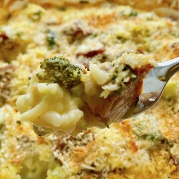 Cheesy Chicken Sausage Broccoli Rice Casserole bite on fork above casserole dish.