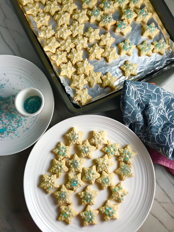 Snowflake Cut Out Sugar Cookies decorated with white glaze and blue sprinkles