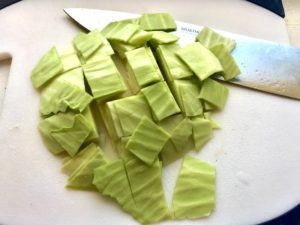 Raw cabbage cut on a cutting board with knife for Detox Cabbage Soup.