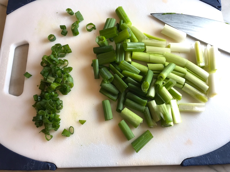 Sliced scallions for Ginger Teriyaki Tofu bowl with noodles, zucchini strips, red peppers.