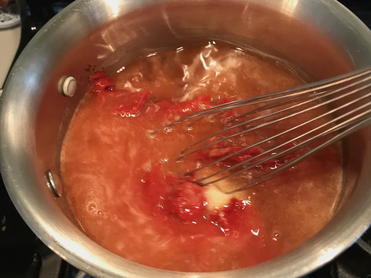 Whisk mixing honey and tomato paste in pot for the Best Honey Ketchup recipe.