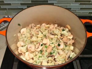 Cauliflower pieces, scallions, and sliced mushrooms cooking in a pot for Creamy Cajun Cauliflower and Beans.