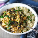 Creamy Cajun Cauliflower and Beans over Quinoa in a bowl. The mild cajun flavors combined with  healthy garbanzo beans, black beans, cauliflower, and mushrooms make this a hearty, creamy, and delicious dish. 