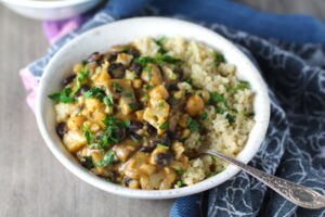 Creamy Cajun Cauliflower and Beans over Quinoa in a bowl. The mild cajun flavors combined with healthy garbanzo beans, black beans, cauliflower, and mushrooms make this a hearty, creamy, and delicious dish.