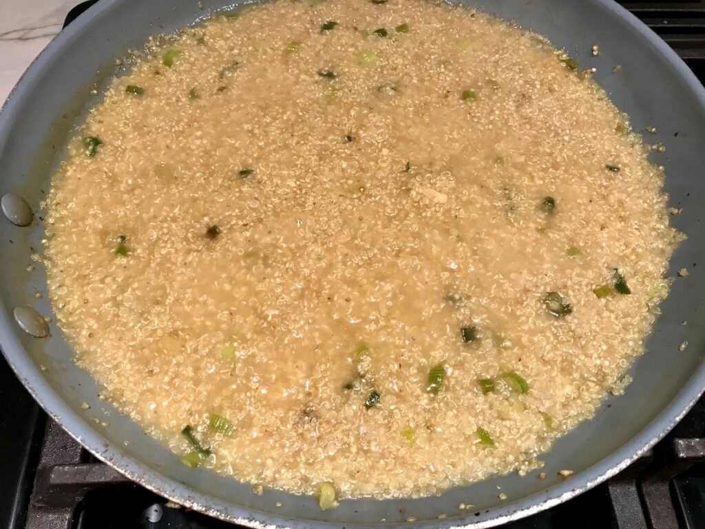 Quinoa risotto cooking in frying pan with scallions and garlic for Creamy Parmesan Mushroom Quinoa Risotto