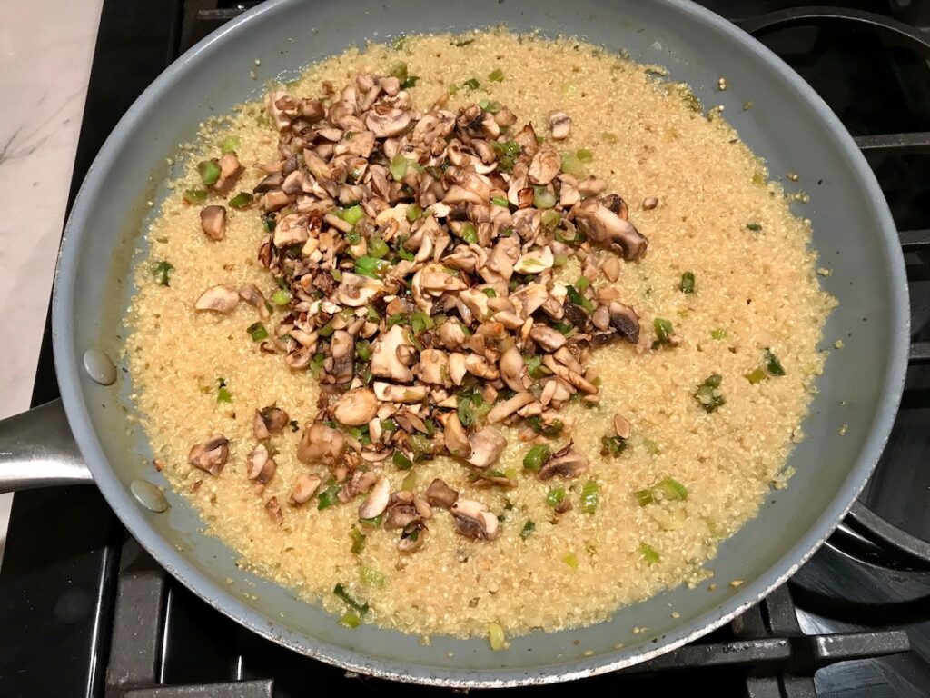 Cooked mushrooms added to cooked Quinoa risotto in frying pan for Creamy Parmesan Mushroom Quinoa Risotto
