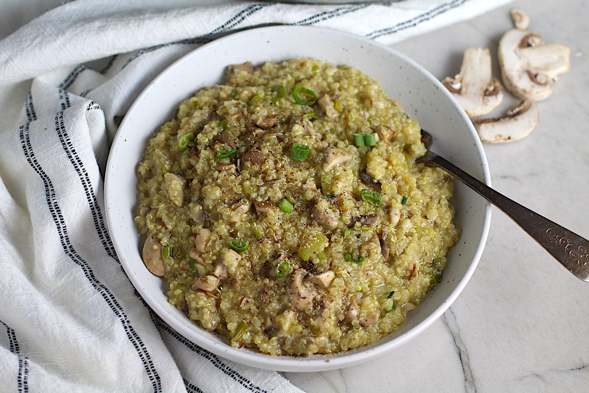 Creamy Parmesan Mushroom Quinoa Risotto in a bowl with fork. This recipe has the traditional garlic flavor in the background and the nuttiness from the Parmesan combined with the meaty earthy flavor of the mushrooms. There is no wine.