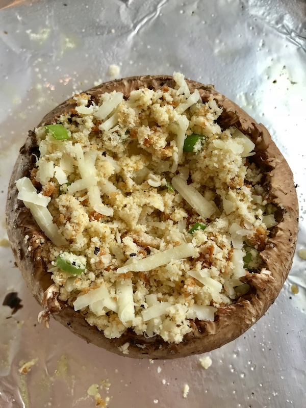 Breadcrumb and cheese filling in the Portabella Mushroom Egg Nests on pan before the egg is added. Portabella mushrooms are filled with garlic, scallion, breadcrumb & Manchego cheese stuffing! Then an egg is baked nestled in the center of all of this goodness.