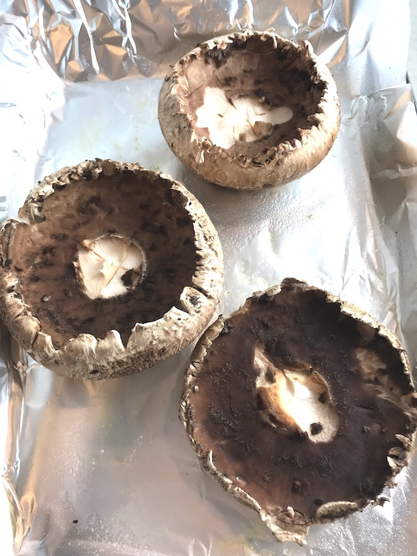 Raw Portobello Mushrooms on pan for the Breakfast Stuffed Mushrooms. Portabella mushrooms are filled with garlic, scallion, breadcrumb & Manchego cheese stuffing! Then an egg is baked nestled in the center of all of this goodness.