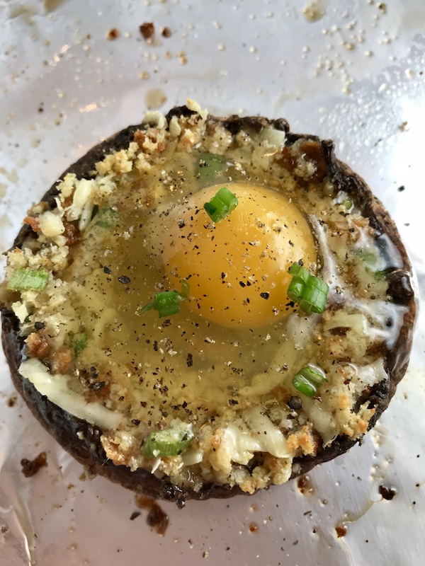 Uncooked Portabella Mushroom Egg Nests on pan. Portabella mushrooms are filled with garlic, scallion, breadcrumb & Manchego cheese stuffing! Then an egg is baked nestled in the center of all of this goodness.