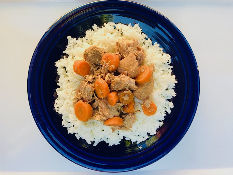 5-Ingredient Slow Cooker Pork Stew cooked and served over white rice on a blow plate. It's an easy and flavorful! Served over Rice, it's a perfect family dinner.