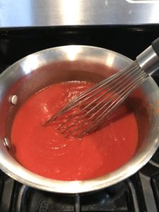 Whisk mixing ketchup ingredients in pot for the Best Sugar Free Ketchup.