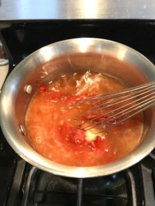 Whisk mixing honey and tomato paste in pot for the Best Sugar Free Ketchup.