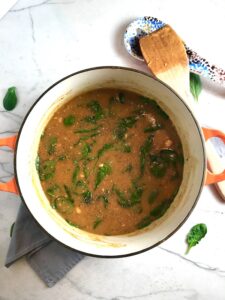 Creamy Tomato Soup in a soup pot on napkin on counter with wood spoon on side. It has Ground Chicken and Spinach is creamy and chunky and has a ton of deep flavor. AND it is healthy! It uses all white meat ground chicken that you cook until it is incredibly browned for some serious flavor. Then tomato paste adds the flavor back drop for the soup and a flour roux plus broth creates the amazing creaminess! Finally Spinach is your veggie boost.