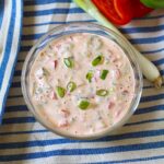 Crunchy Mayo and Ketchup dipping sauce with pickles, red peppers, and scallions on a blue and white striped towel with whole scallion and cut red pepper sitting next to it.