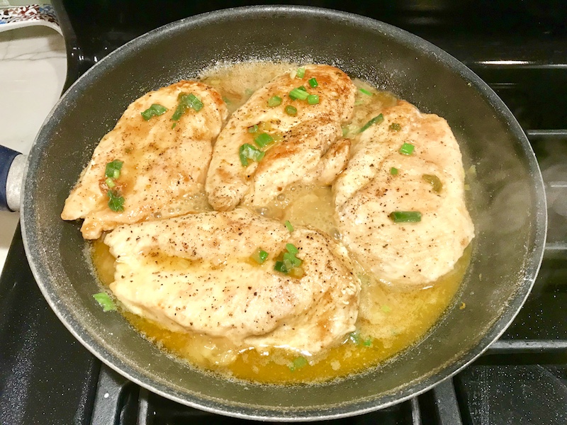 Orange Brown Butter Sauce Chicken cooking in a skillet on stove.