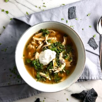 Chicken Tortilla Soup in a bowl with sour cream on top and tortilla chips on side. It's quick, it's easy, it's delicious AND...it's an all-in-one balanced dish because I have added KALE! Done in 30 minutes!