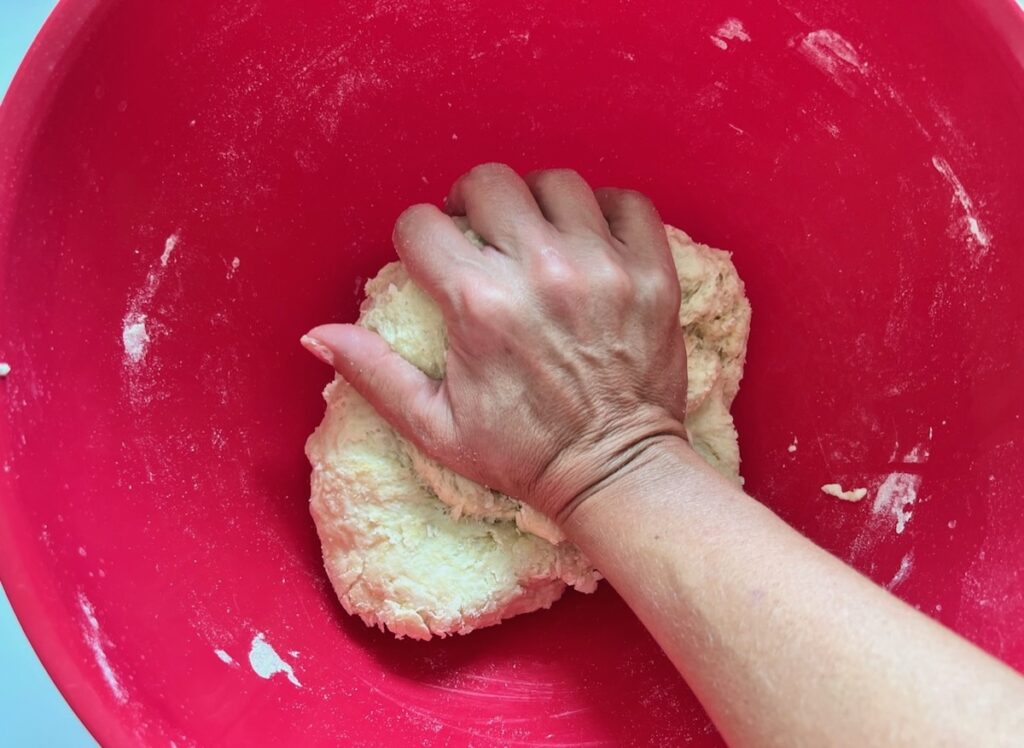 Hand kneading pizza dough in a large bowl for Chicago Pizza with Chicken Sausage.