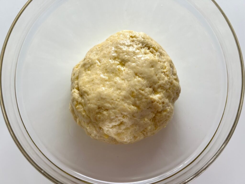 Pizza dough ball oiled in a large glass bowl so it can rise for Chicago Pizza with Chicken Sausage.