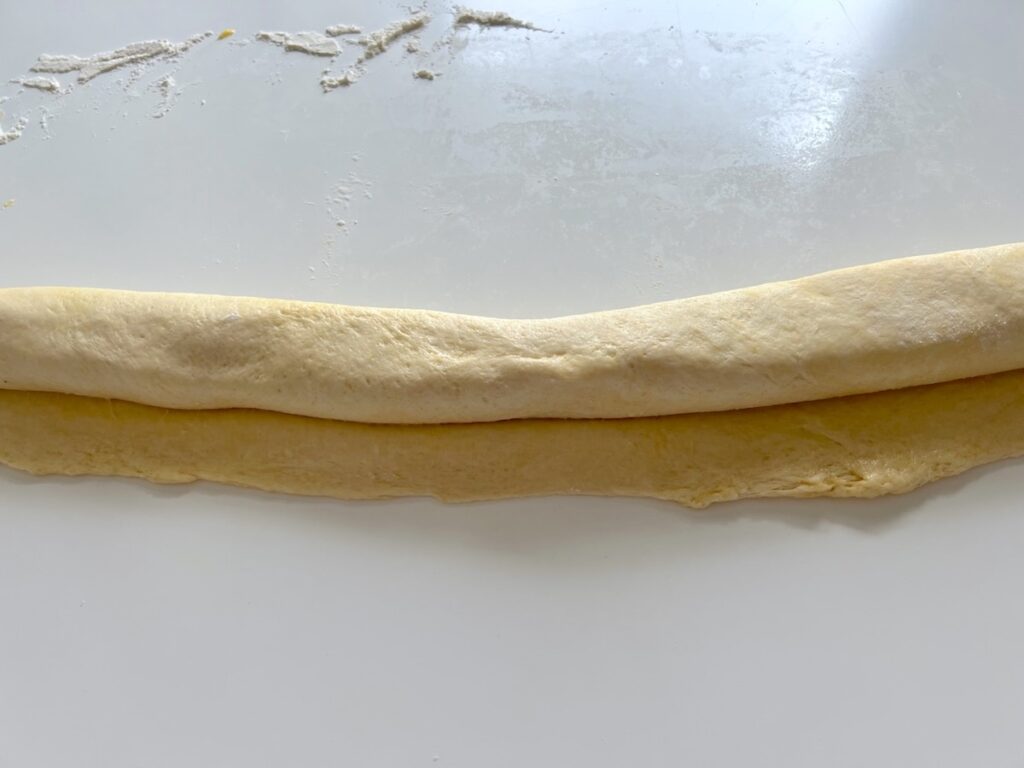 Pizza dough spread with softened butter and then rolled into a log before cutting in half for Chicago Pizza with Chicken Sausage.