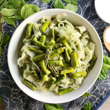Pasta with spinach, asparagus, cauliflower sauce in bowl on blue towel