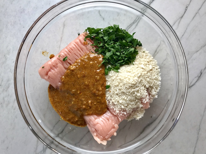 Moroccan Spices, breadcrumbs, raw ground turkey, and parsley in a bowl for Turkey Meatballs for Pita Bread Sandwiches Recipe.