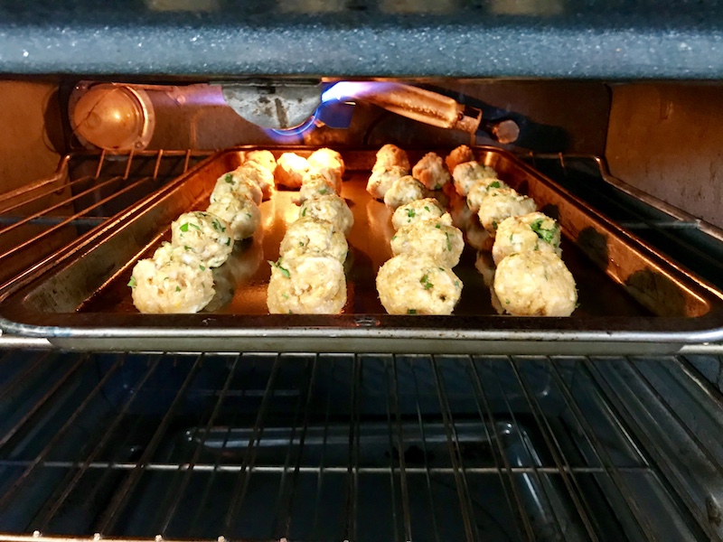 Moroccan turkey meatballs on a sheet pan under broiler in oven to go into Pita Bread Sandwiches Recipe.