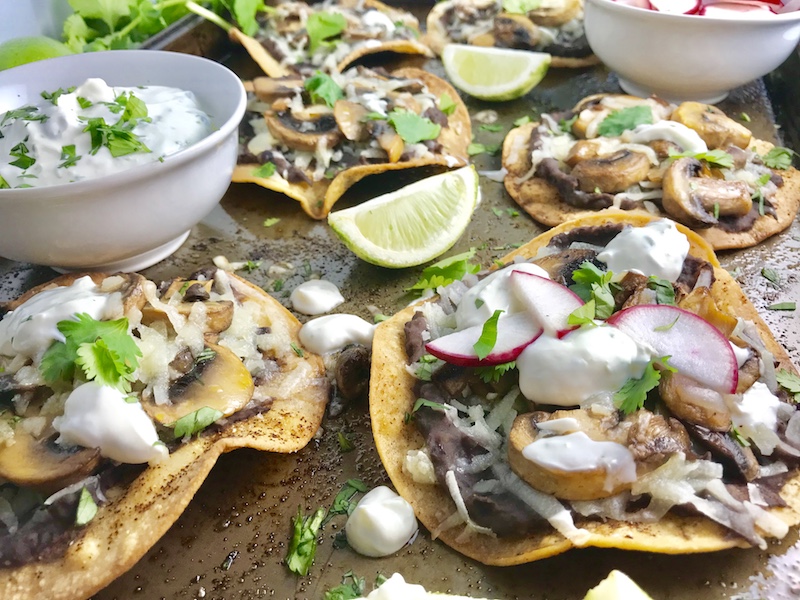 Mushroom and Black Bean Tostadas with Manchego Cheese, and Cilantro Lime Cream are crazy good! The tortillas are baked until crunchy, then topped with homemade refried black beans, nutty aged Manchego Cheese, sautéed mushrooms, and then baked until the cheese is melted. Top with cool cilantro lime cream, crisp radishes, and fresh cilantro. Simple, Gluten-Free, Vegetarian, Delicious!
