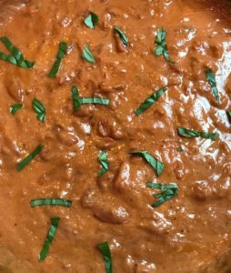 sour cream Tomato Sauce close up with basil slices on top.
