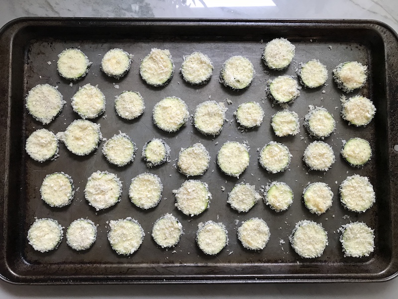 Uncooked Parmesan coated Zucchini chips cooked on pan. Showing how to roast zucchini slices.