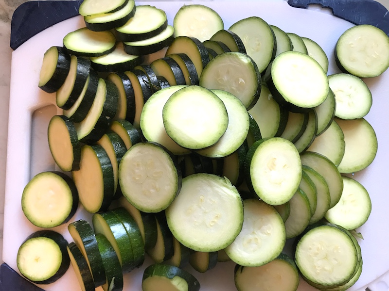 Raw slices of Zucchini on cutting board.Learn how to roast zucchini slices.