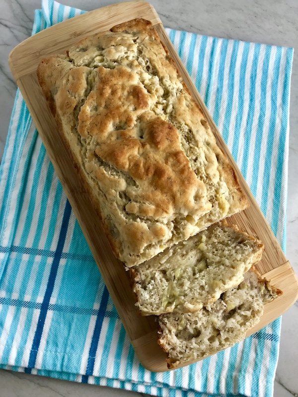 4 Ingredient Banana Bread with Pancake Mix sliced on a wood cutting board on blue towel. It could not be any EASIER! It is moist, delicious, and so incredibly simple that you can whip it up in 5 minutes, then bake it in the oven.