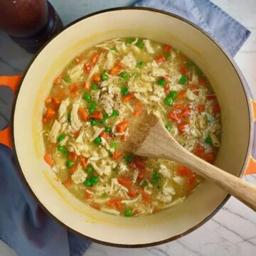 5-Ingredient Creamy Chicken and Vegetable Soup in a pot on counter with wooden spoon.