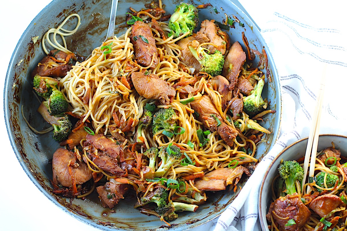 Peanut Teriyaki Chicken & Broccoli with Noodles in a bowl with chopsticks on a towel on table.
