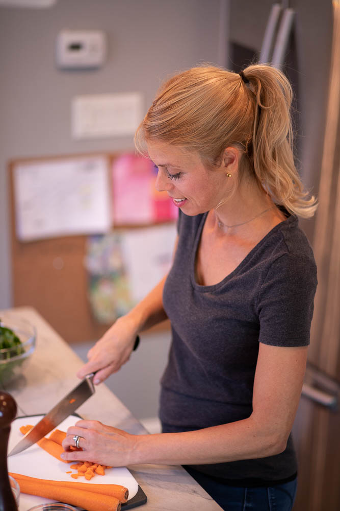 Carrie prepping food with knife at counter in kitchen.