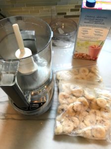 Mini Food Processor on counter with frozen bananas in baggies and almond milk carton. Banana Ice Cream is literally just 2 ingredients, Frozen Bananas and Almond Milk. Add in crunchy Graham Crackers as the 3rd ingredient and you have a delicious healthy Banana Ice Cream Sandwich! If you have never tried banana ice cream, you are in for a treat! It tastes just like soft serve ice cream.