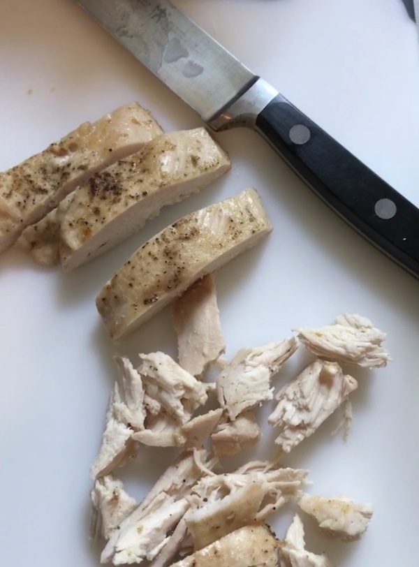 Roasted Chicken sliced and then shredded on a cutting board for the Lemon Basil Chicken Salad with Grapes recipe. This recipe is simple, but the taste is anything but simple. It has layers of flavors and textures. You get the hearty texture of the chicken, brightness from the lemon, the fresh and fragrant basil, a slight bite from the onion, and a huge juicy burst of sweetness from the grapes.