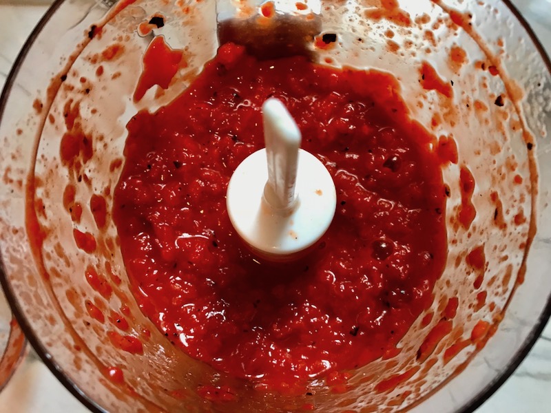 Roasted Red Peppers blended in a food processor for Roasted Red Pepper Gazpacho recipe from talkingmeals.com.