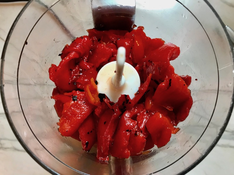 Drained roasted red peppers in a food processor for Roasted Red Pepper Gazpacho from www.talkingmeals.com