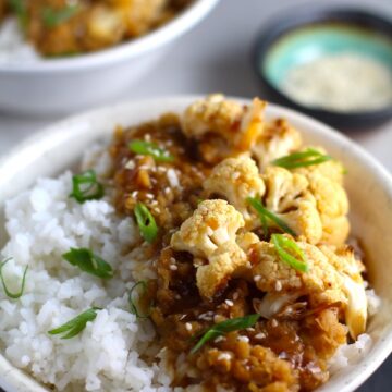 This Korean Rice Bowl on counter with Rice, Lentils and Cauliflower. This recipe is da bomb, exploding with flavor! The rice soaks up the sauce, which gives you a nutty, salty flavor from sesame oil and soy sauce, a warm and zesty kick from ginger and garlic, and sweetness from honey to balance it all out. Lentils and cauliflower give a meaty bite.