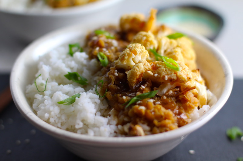 This Korean Rice Bowl on counter with Rice, Lentils and Cauliflower. This recipe is da bomb, exploding with flavor! The rice soaks up the sauce, which gives you a nutty, salty flavor from sesame oil and soy sauce, a warm and zesty kick from ginger and garlic, and sweetness from honey to balance it all out. Lentils and cauliflower give a meaty bite.